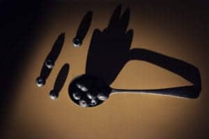 A silver spoon holds several blueberries, casting a prominent shadow on a beige surface. Scattered blueberries lie nearby, their shadows elongating across the background, creating a visually intriguing pattern that would captivate any Oldham photographer's eye.