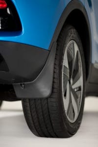 Close-up view of the rear tire of a blue vehicle, highlighting the tire tread and the design of the wheel rim. The lower part of the car body and a mud guard are also visible, perfectly capturing the details while photographing the brand new MG.