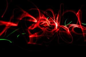 Abstract image of swirling red and green light trails against a black background, creating dynamic, flowing shapes and a sense of movement—an impressive example of light painting photography.