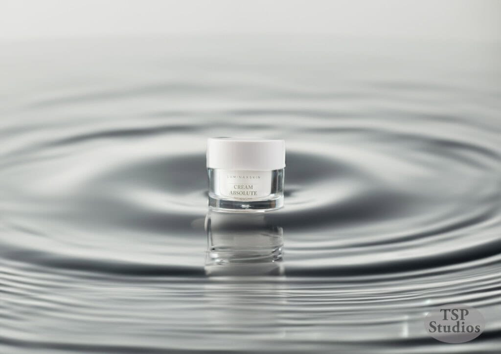 A small jar of skin cream, labeled "Cream Absolute," is centered amid concentric ripples on a smooth water surface. The scene conveys a sense of tranquility and the product's effectiveness. The image is branded with "TSP Studios" in the bottom right corner.