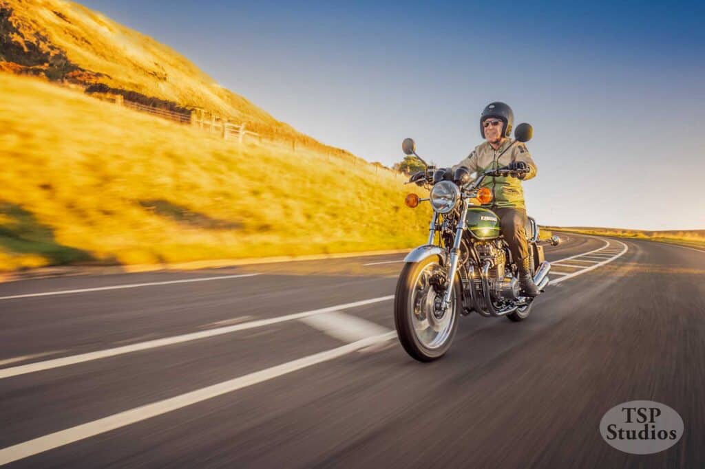 a kawasaki at speed on a sweeping bend in the golden hour, showing the joy of riding a bike
