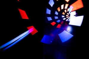Spiraling red, white, and blue rectangular light shapes create a tunnel effect against a dark background, giving an abstract, futuristic impression.