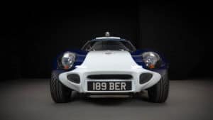 Front view of a classic white sports car with blue accents, round headlights, and a black license plate reading "189 BER," photographed against a dark background.